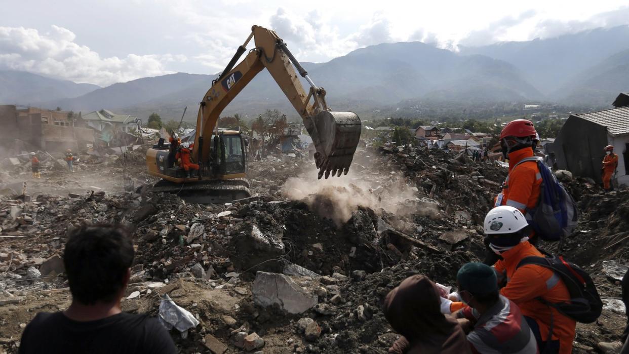 Rettungskräfte beobachten einen Bagger, der sich durch die Trümmer gräbt und nach Erdbeben-Opfern sucht. Foto: Dita Alangkara/AP