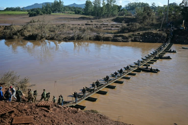 Varias personas cruzan el río Forquilha, de Arroio do Meio a Lajeado, en Brasil, a través de un puente peatonal que sustituye al de Rodovia RS130, arrasado por las inundaciones, el 15 de mayo de 2024 (Nelson Almeida)