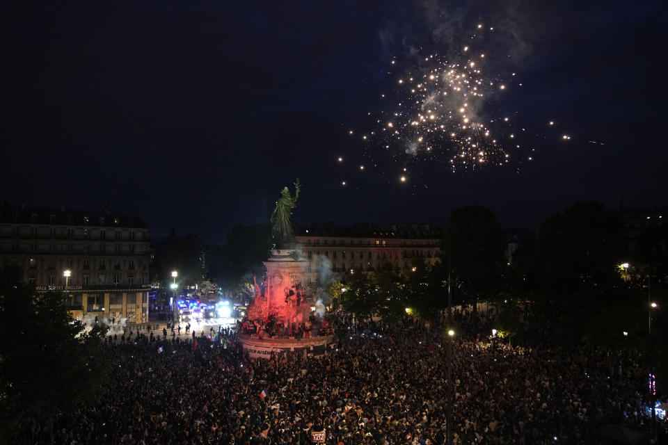 Personas lanzan fuegos artificiales al reunirse en la plaza de la República tras la revelación de los resultados preliminares de la segunda vuelta de las elecciones legislativas, en París, Francia, el domingo 7 de julio de 2024. (AP Foto/Christophe Ena)