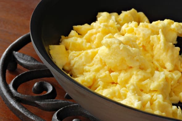 Freshly prepared scrambled eggs in healthy, eco friendly, ceramic nonstick skillet on trivet.  Macro with shallow dof.