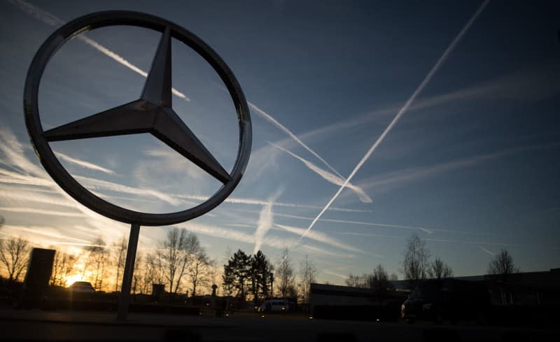 The sun rises behind a Mercedes star on the Mercedes-Benz plant. Sebastian Gollnow/dpa