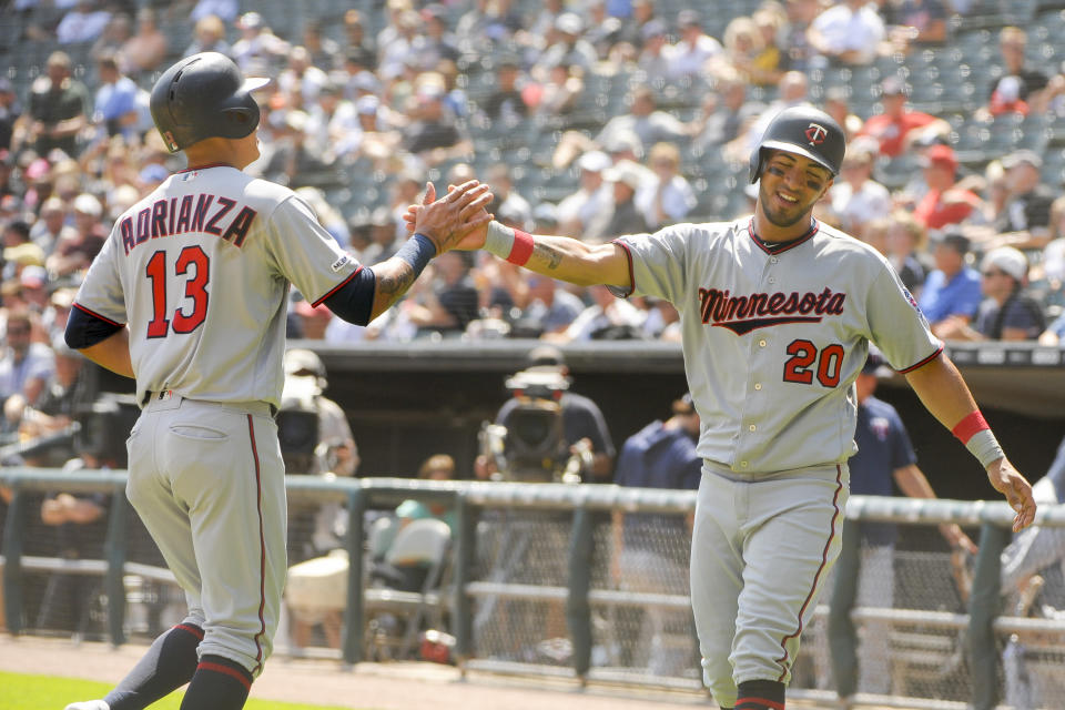 Minnesota Twins' Ehire Adrianza (13) and Eddie Rosario (20) celebrate a two-run RBI single by C.J. Cron (24) during the first inning of a baseball game Thursday, Aug. 29, 2019, in Chicago. (AP Photo/Mark Black)