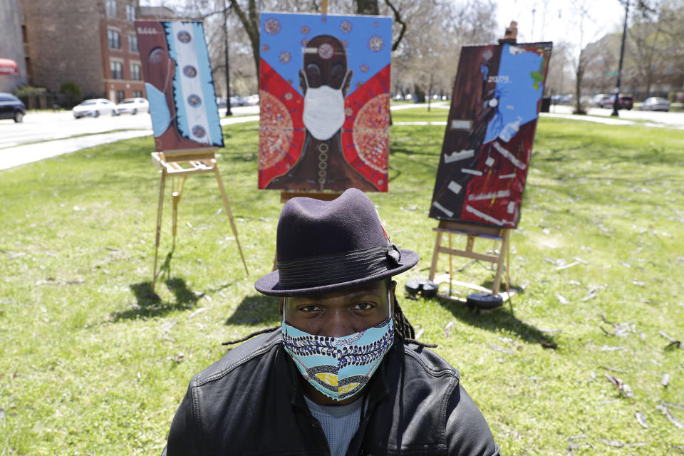 In this Tuesday, April 21, 2020 photo, Obi Uwakwe poses with his painting in Chicago. Uwakwe is an artist/photographer and submitted his art work to the the Illinois State Museum, which is documenting what daily life is like for Illinois families during the coronavirus pandemic. (AP Photo/Nam Y. Huh)