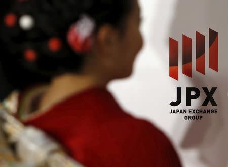 A logo of Japan Exchange Group Inc. is seen next to a woman, dressed in ceremonial kimono at the Tokyo Stock Exchange (TSE), in Tokyo, Japan, January 4, 2016. REUTERS/Yuya Shino/File Photo