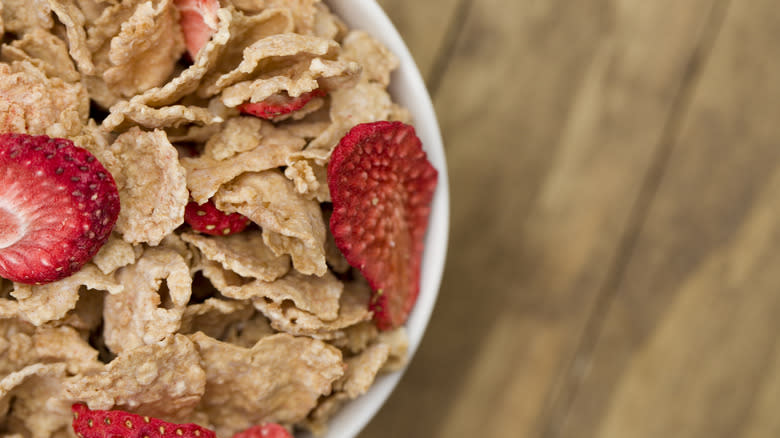 breakfast cereal flakes with dried strawberries in white bowl