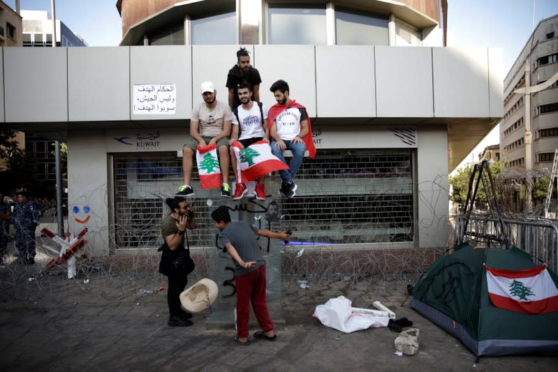 Protesters sit on a phone box at a demonstration organised by students during ongoing anti-government protests in Beirut