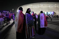 Fans with Iranian and US flags over their shoulders stand outside the stadium before the World Cup group B soccer match between Iran and the United States at the Al Thumama Stadium in Doha, Qatar, Tuesday, Nov. 29, 2022. (AP Photo/Hassan Ammar)