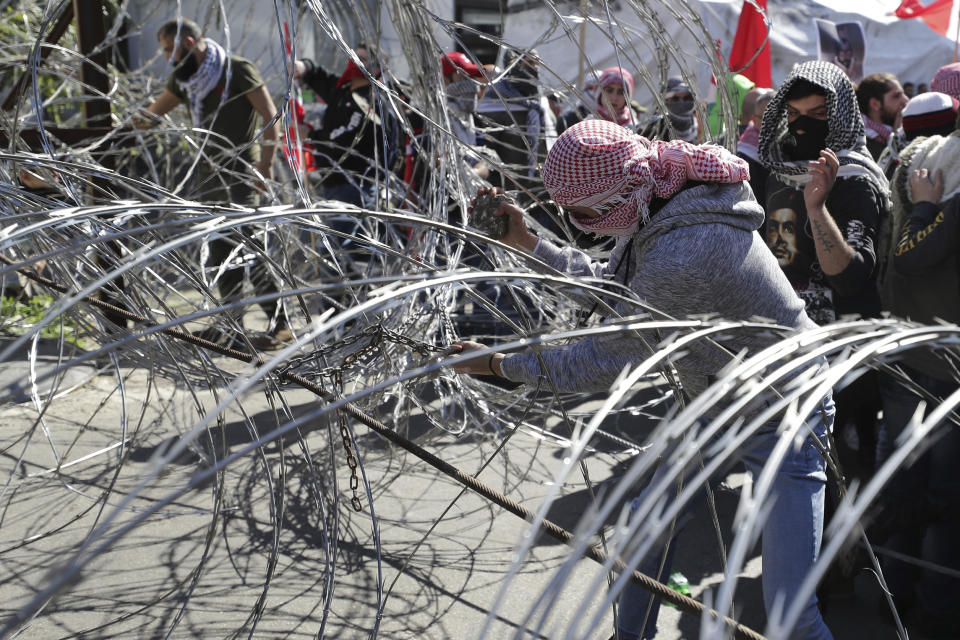 Protesters try to remove barbed wires that block a road leading to the U.S. embassy during a protest is held against the proposed peace deal for the Middle East by President Donald Trump, in Aukar, east of Beirut, Lebanon, Sunday, Feb. 2, 2020. Hundreds of Lebanese and Palestinians demonstrated Sunday near the U.S. embassy in Lebanon in rejection to a White House plan for ending the Israeli-Palestinian conflict. (AP Photo/Hassan Ammar)