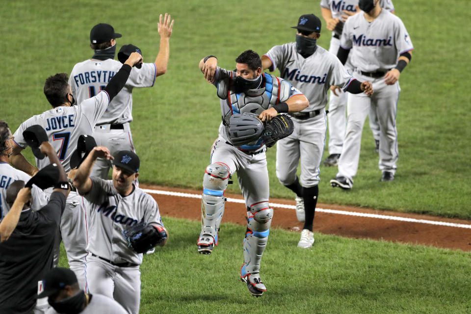 Miami Marlins catcher Francisco Cervelli, center, reacts he engages with teammates in a social distant celebration after defeating the Baltimore Orioles 4-0 during a baseball game, Tuesday, Aug. 4, 2020, in Baltimore. (AP Photo/Julio Cortez)