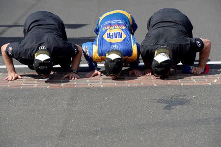 May 29, 2016; Indianapolis, IN, USA; IndyCar Series driver Alexander Rossi (middle) kisses the yard of bricks after winning the 100th running of the Indianapolis 500 at Indianapolis Motor Speedway. Mandatory Credit: Michael Madrid-USA TODAY Sports