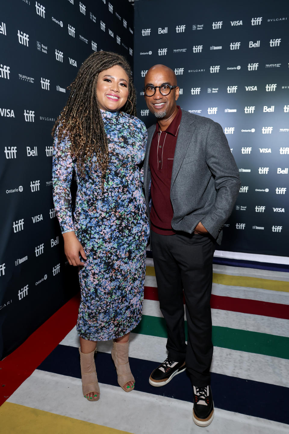 Tracy Oliver and Tim Story smiling on red carpet