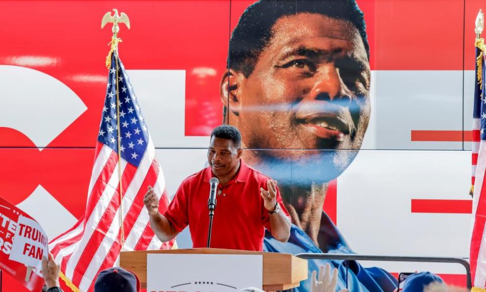 Herschel Walker in front of a bus with his face on it.