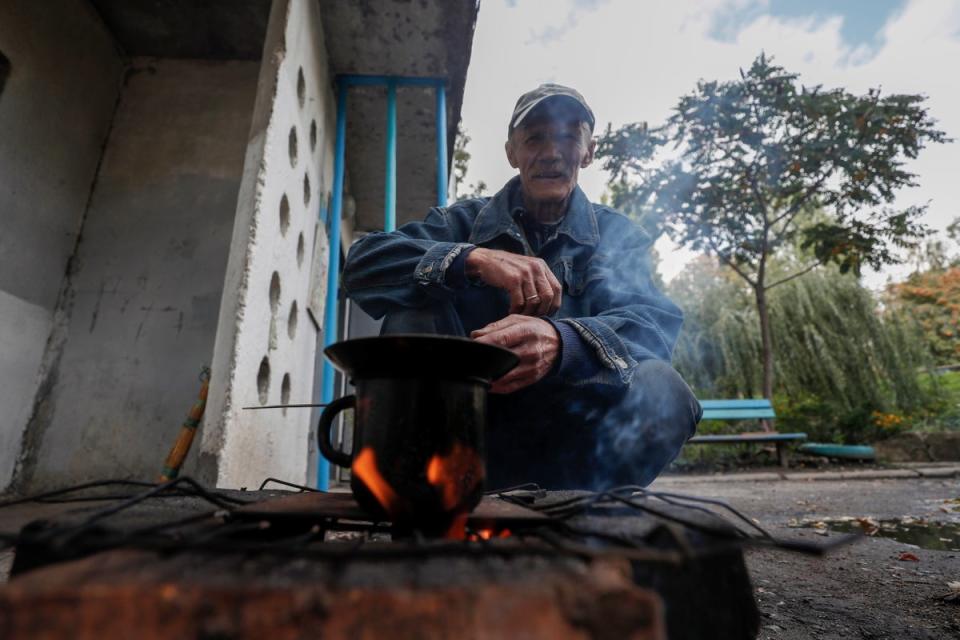 Batslava, an elderly Ukrainian, preparing soup  on a stove in the newly liberated city of Kupyansk, east of Kharkiv, on Monday (EPA)