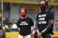 Ferrari driver Sebastian Vettel of Germany, left, and Mercedes driver Lewis Hamilton of Britain, right, stand against racism in the pit lane prior the Styrian Formula One Grand Prix race at the Red Bull Ring racetrack in Spielberg, Austria, Sunday, July 12, 2020. (Mark Thompson/Pool via AP)