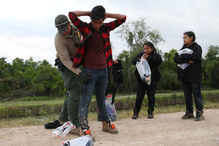 A border patrol agent apprehends immigrants who illegally crossed the border from Mexico into the U.S. in the Rio Grande Valley sector, near McAllen, Texas, U.S., April 3, 2018. REUTERS/Loren Elliott