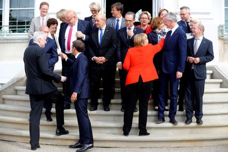 German Chancellor Angela Merkel nad French President Emmanuel Macron arrive for a family photo before a meeting with the Franco-German Ministerial Council in Meseberg, Germany. REUTERS/Hannibal Hanschke