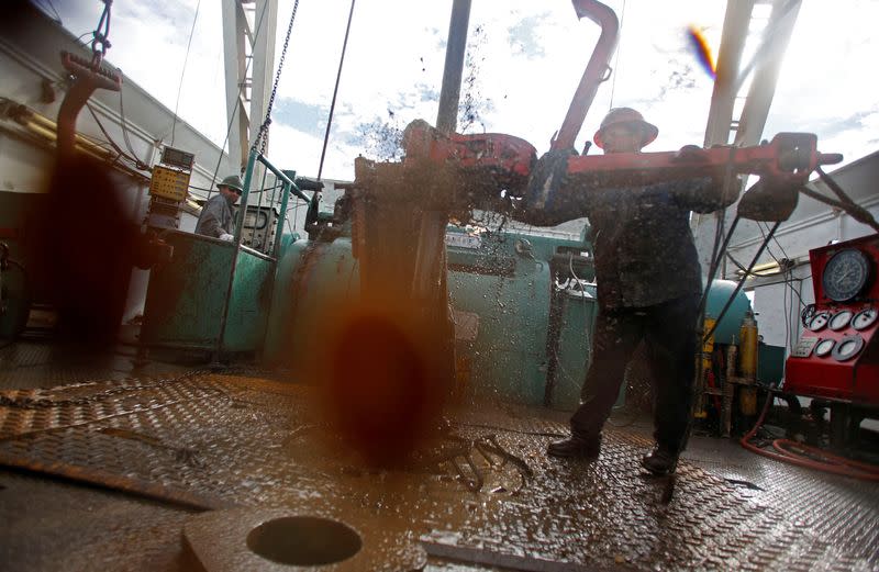 FILE PHOTO: Roughnecks wrestle pipe on an oil drilling rig outside Watford