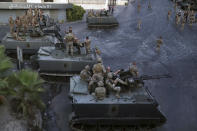 Lebanese army soldiers sit on their armored vehicles as they deployed to contain the tension after heavy fire in the coastal town of Khaldeh, south of Beirut, Lebanon, Sunday, Aug. 1, 2021. At least two people were killed on Sunday south of the Lebanese capital when gunmen opened fire at the funeral of a Hezbollah commander who was killed a day earlier, an official from the group said. (AP Photo/Bilal Hussein)