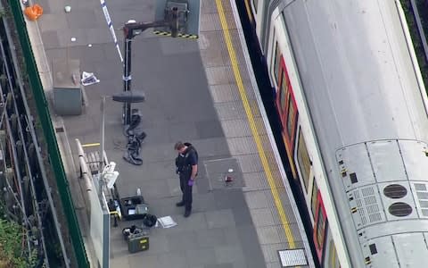 a police officer works at the Parsons Green Underground Station after an explosion  - Credit: AP