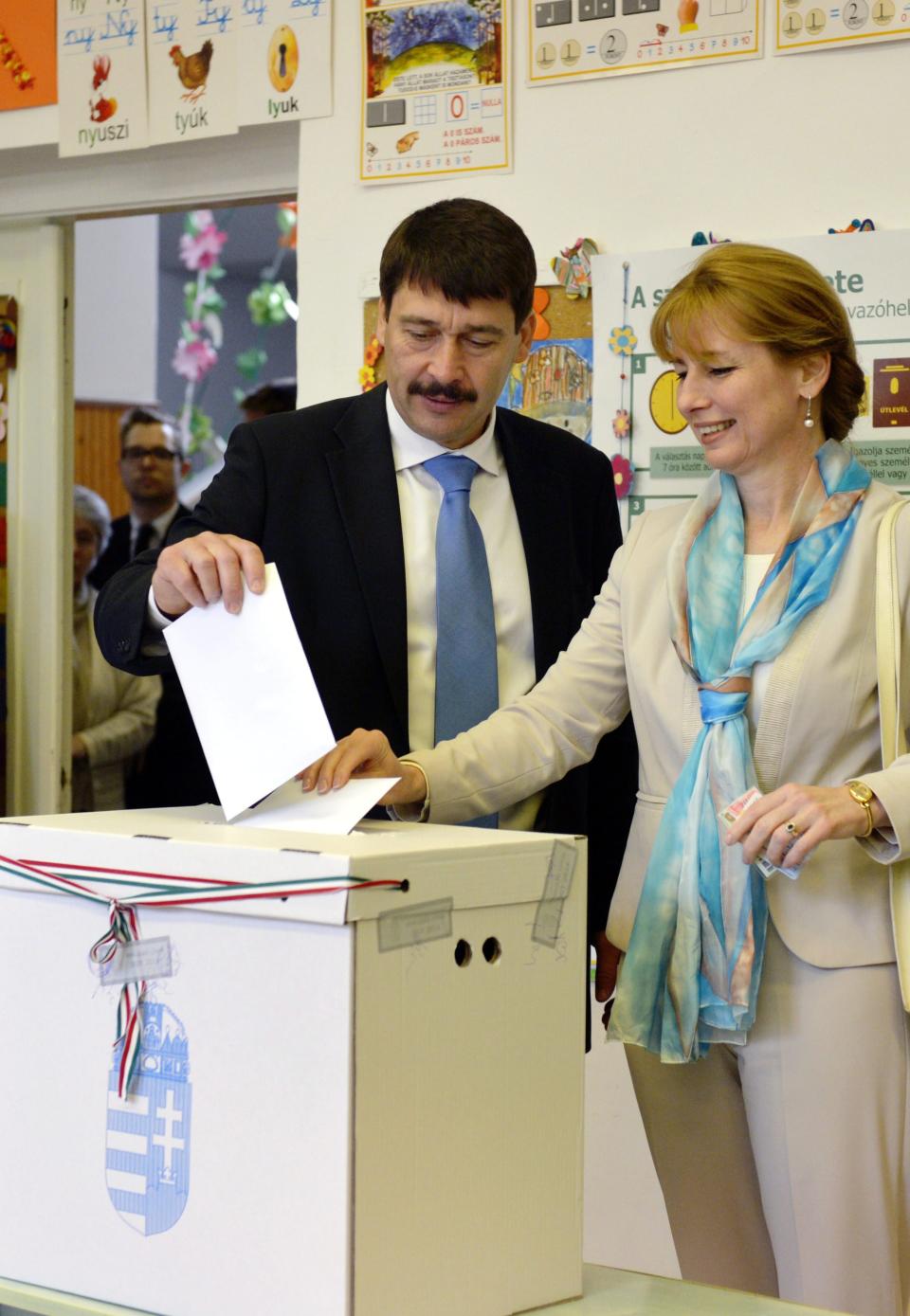 Hungarian President Janos Ader and his wife Anita Herczegh cast their vote at a polling station in Budapest during the parliamentary elections in Hungary, Sunday April 6, 2014. Hungary's governing party is tipped to win parliamentary elections Sunday, while a far-right party is expected to make further gains, according to polls. Prime Minister Viktor Orban's Fidesz party and its small ally, the Christian Democrats, are expected to win easily and they may even retain the two-thirds majority in the legislature gained in 2010 which allowed them to pass a new constitution, adopt unconventional economic policies, centralize power and grow the state's influence at the expense of the private sector. (AP Photo/Laszlo Beliczay)