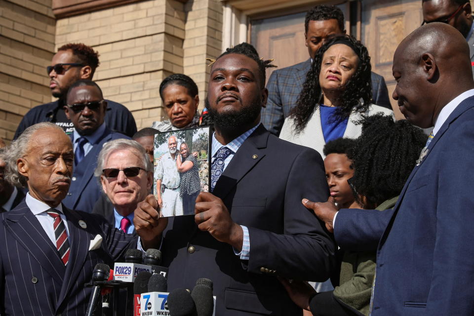 Marcus Talley, surrounded by others at the news conference, shows a photo of his mother, Geraldine Talley, who was killed in the Buffalo supermarket shooting.