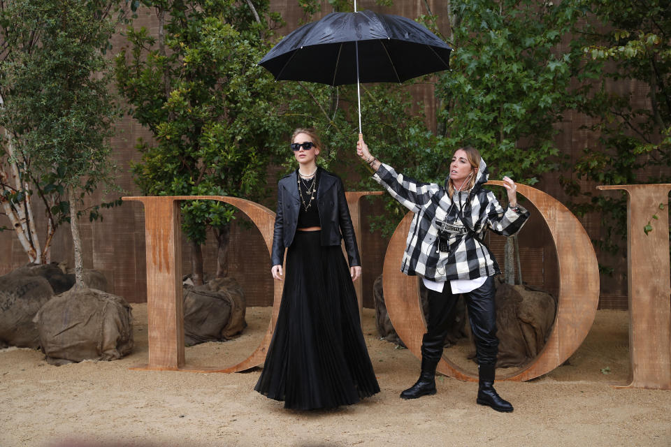 An assistant protects American actress Jennnifer Lawrence during a photocall before Dior's Ready To Wear Spring-Summer 2020 collection, unveiled during the fashion week, in Paris, Tuesday, Sept. 24, 2019. (AP Photo/Francois Mori)