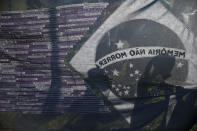 FILE - In this June 23, 2021 file photo, the shadows of protesters are cast on a Brazilian flag covered with the names of COVID-19 victims outside Congress during a protest against the high death toll from the pandemic in Brasilia, Brazil. Coronavirus-related deaths in Brazil have surpassed 500,000 while Senate hearings on President Jair Bolsonaro's response to the virus continue. (AP Photo/Eraldo Peres)