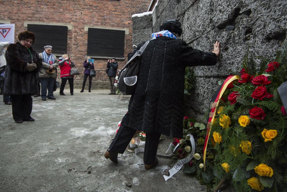 Holocaust survivors pay tribute to fallen comrades at the 'death wall' execution spot in the former Auschwitz concentration camp in Oswiecim, Poland, on the 70th anniversary of the liberation of the Nazi death camp on January 27, 2015. Seventy years after the liberation of Auschwitz, ageing survivors and dignitaries gather at the site synonymous with the Holocaust to honour victims and sound the alarm over a fresh wave of anti-Semitism. 