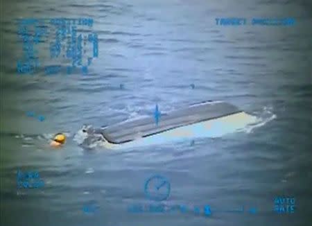 An MH-60 Jayhawk rescue helicopter crew from Air Station Clearwater, Florida, locates a capsized boat and searches for two missing 14-year-old boys, 77 miles (124 kms) east of Ponce Inlet, Florida in this U.S. Coast Guard picture from video taken July 26, 2015 and released July 27. REUTERS/U.S. Coast Guard/Handout