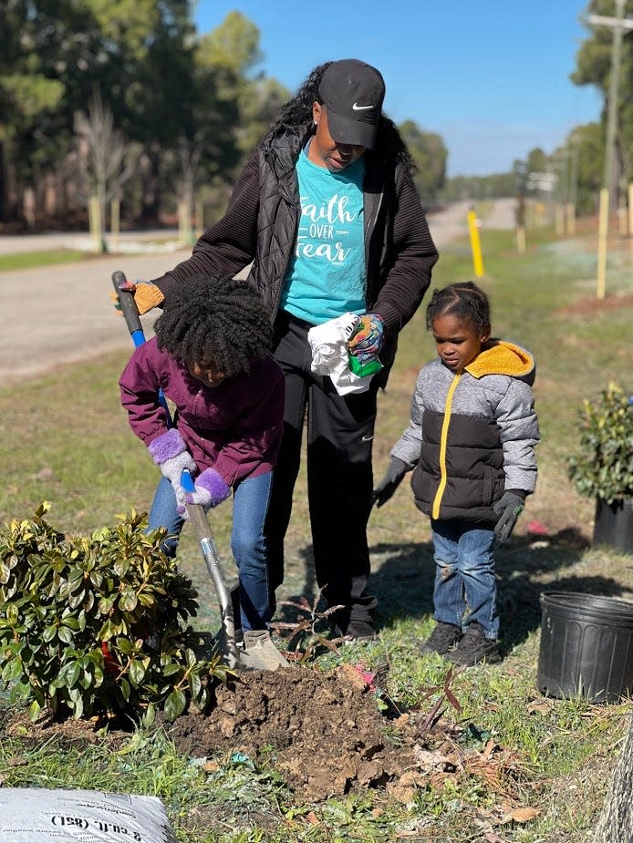 Addie Clark, 7, and Cyson Clark, 2, along with their mother, Taylor Clark, help plant azalea bushes Jan. 19, 2022, for an Arbor Day celebration at Fort Bragg's newest park, Liberty Park.