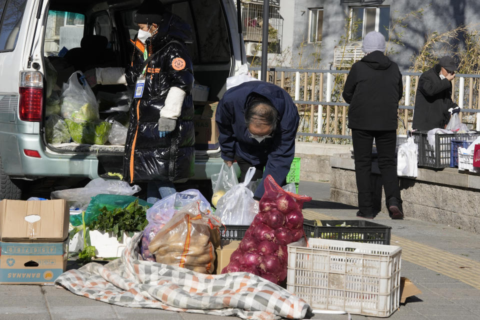 A resident buys vegetable from a street vendor in Beijing, Friday, Dec. 16, 2022. A week after China dramatically eased some of the world's strictest COVID-19 containment measures, uncertainty remained Thursday over the direction of the pandemic in the world's most populous nation. (AP Photo/Ng Han Guan)