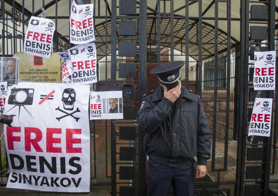 An Interior Ministry officer stands as Ukrainian photojournalists take part in a rally in support of freelance photographer Sinyakov in front of the Russian embassy in Kiev