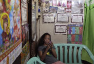 In this photo taken Dec. 4, 2012, Filipino slum dweller Jessa Balote uses her smartphone beside a wall filled with her ballet certificates and pictures inside her cramped home at a place called Aroma in Tondo, Manila, Philippines. Balote, who used to tag along with her family as they collect garbage at a nearby dumpsite, is a scholar at Ballet Manila's dance program. As an apprentice, she makes around 7,000 pesos ($170) a month, sometimes double that, from stipend and performance fees. (AP Photo/Aaron Favila)