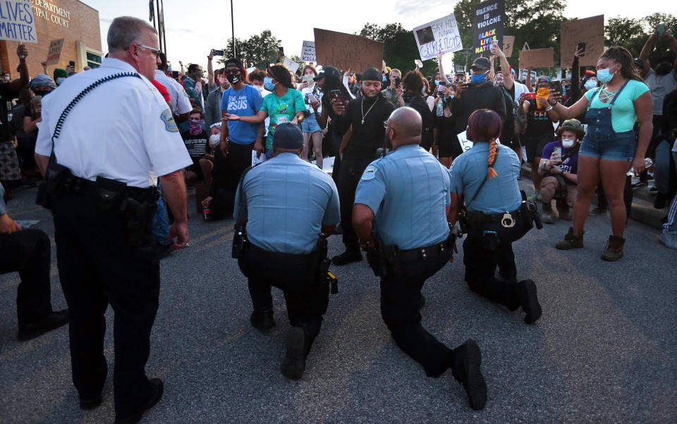 Police officers from Ferguson, Missouri, join protesters to remember George Floyd by taking a knee in the parking lot of the police station on Saturday. (Photo: ASSOCIATED PRESS)