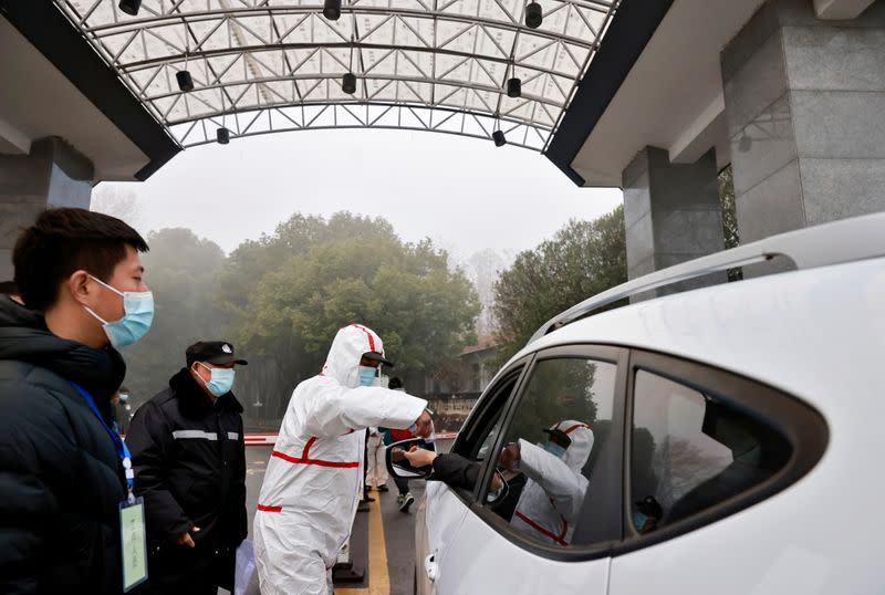 Security personnel check people's temperature during the visit by members of the World Health Organization (WHO) team tasked with investigating the origins of the coronavirus disease (COVID-19), at the Hubei provincial center for disease control in Wuhan