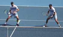 Mike Bryan, left, of the U.S. and his brother Bob play during their third round doubles match against Croatia's Ivan Dodig and Slovakia's Filip Polasek at the Australian Open tennis championship in Melbourne, Australia, Monday, Jan. 27, 2020. (AP Photo/Dita Alangkara)