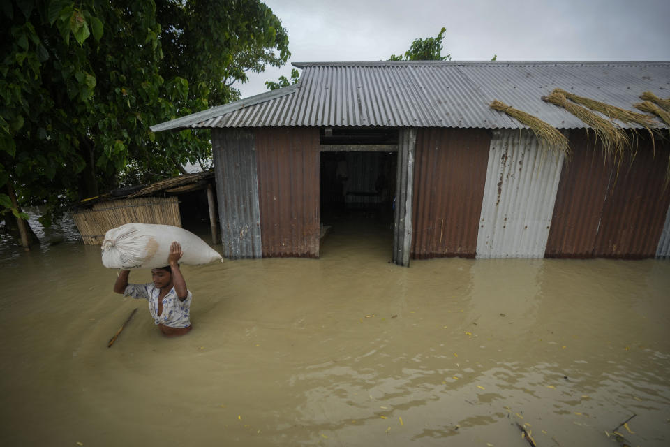 A flood victim carries a sack of rice from his submerged house in Sildubi village in Morigaon district in the northeastern state of Assam, India, Tuesday, July 2, 2024. Floods and landslides triggered by heavy rains have killed more than a dozen people over the last two weeks in India's northeast. (AP photo/Anupam Nath)