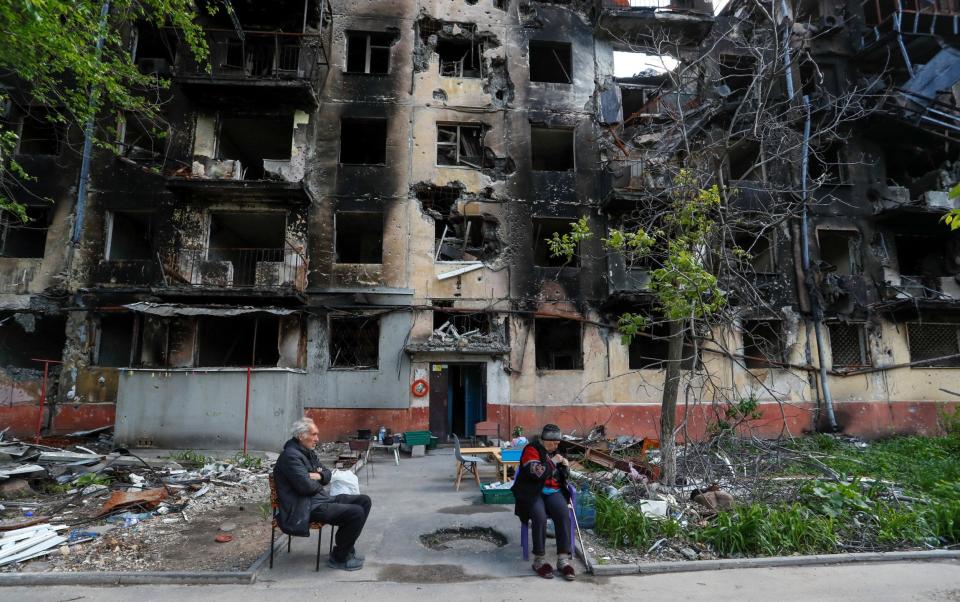 Elderly Mariupol residents sit in a courtyard near a block of flats destroyed by the Russians - REUTERS/Alexander Ermochenko