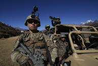 US army soldiers of 2nd Brigade of the 11th Airborne Division fires with Indian army soldiers pose in front of an all terrain vehicle during Indo-US joint exercise or "Yudh Abhyas, in Auli, in the Indian state of Uttarakhand, Tuesday, Nov. 29, 2022. India’s defence ministry statement said the joint exercise is conducted annually with the aim of exchanging best practices, tactics, techniques and procedures between the armies of the two nations. The training schedule focuses on employment of an integrated battle group under Chapter VII of the UN Mandate. The schedule will include all operations related to peace keeping & peace enforcement. (AP Photo/Manish Swarup)