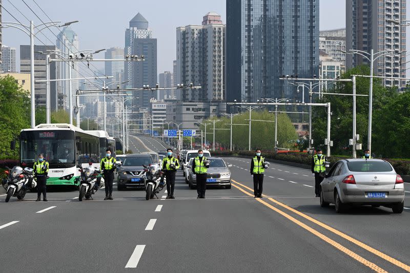 Traffic police officers and vehicle drivers observe a moment of silence on a road in Wuhan