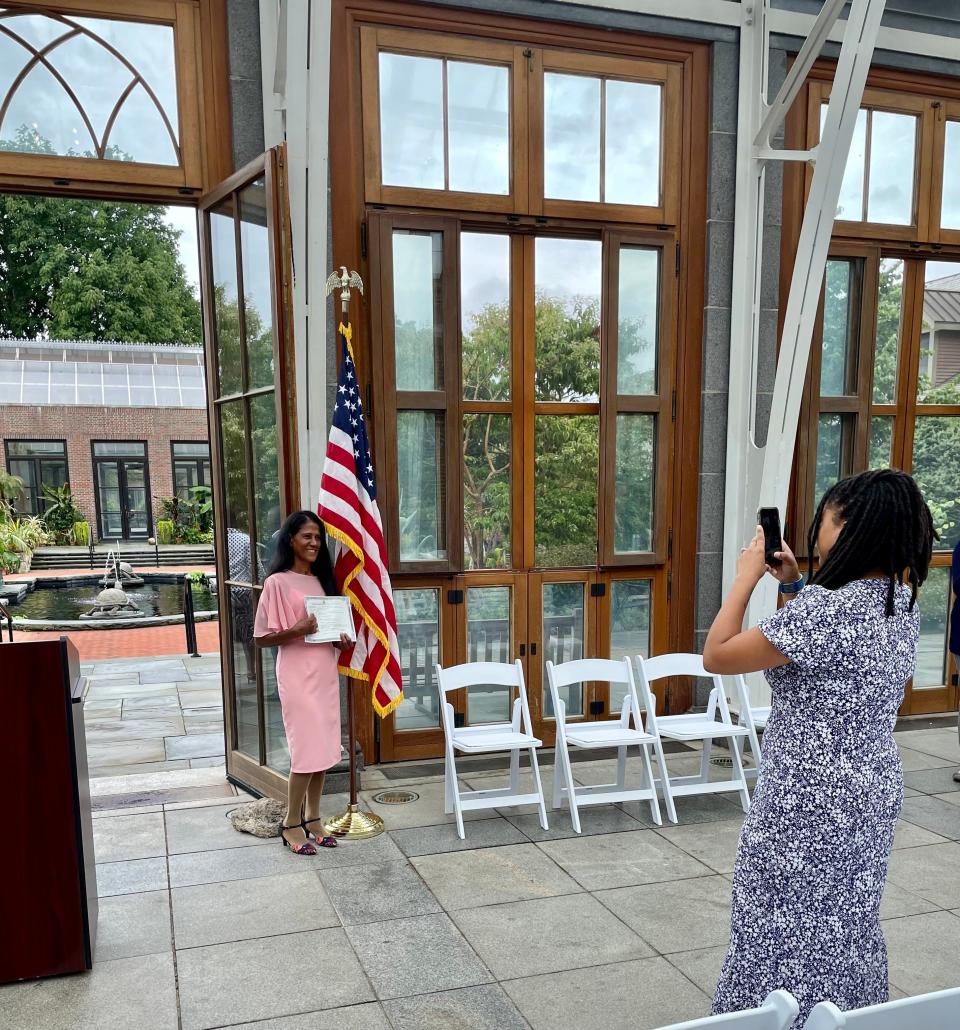 Geovanis Trinidad De Flores, left, poses with her certificate while her daughter, Johanna Wallace, takes a photo, following the naturalization ceremony at the New England Botanic Garden in Boylston.