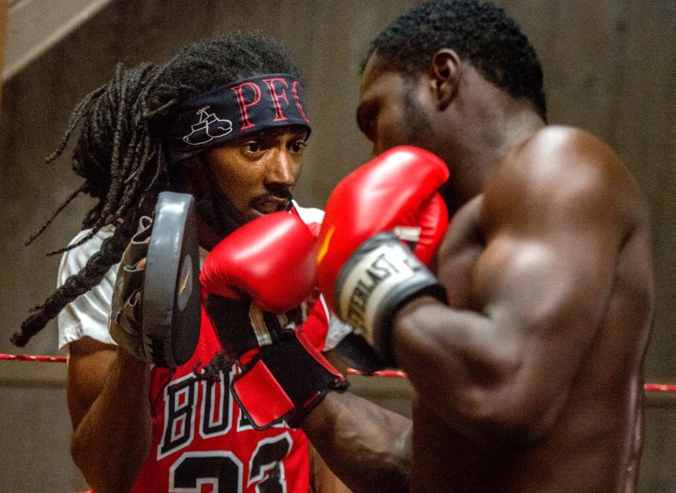 Peoria Fight Club creator Robert Bryant, left, gets in close as he works out with his middleweight champ Shuntez Young during a recent training session at Hot Spot Tattoo and Piercing in Downtown Peoria. [MATT DAYHOFF/JOURNAL STAR]