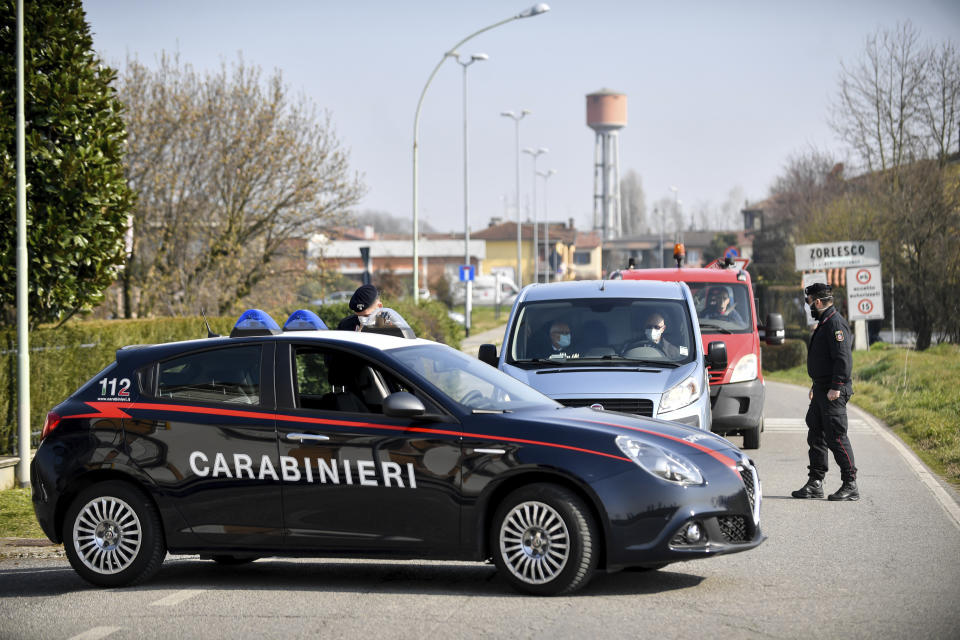 Carabinieri (Italian paramilitary police) officers set a road block in Zorlesco, Northern Italy, Monday, Feb. 24, 2020. Italy scrambled to check the spread of Europe's first major outbreak of the new viral disease amid rapidly rising numbers of infections. Road blocks were set up in at least some of 10 towns in Lombardy at the epicenter of the outbreak, to keep people from leaving or arriving. (Claudio Furlan/Lapresse via AP)