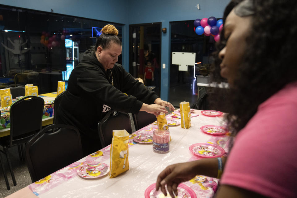 Raquel Ayala sets a table for the birthday party of her two youngest grandchildren at Urban Air Adventure Park, Sunday, Jan. 21, 2024, in North Riverside, Ill. Ayala is currently caring for her daughter Crystal Martinez's five children while she is incarcerated downstate, although she was recently granted a reduced sentence under Illinois' gender-based violence act. (AP Photo/Erin Hooley)