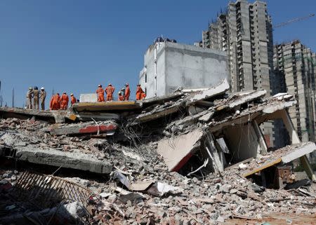 Rescue workers look for survivors amidst the rubble at the site of a collapsed residential building at Shah Beri village in Greater Noida, July 18, 2018. REUTERS/Adnan Abidi