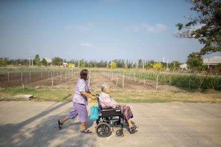 Sampao Jantharun (L), 78, assists Somjit Phuthasiri, 90, on a wheelchair as they head to their home at Wellness Nursing Home Center in Ayutthaya, Thailand, April 9, 2016. REUTERS/Athit Perawongmetha