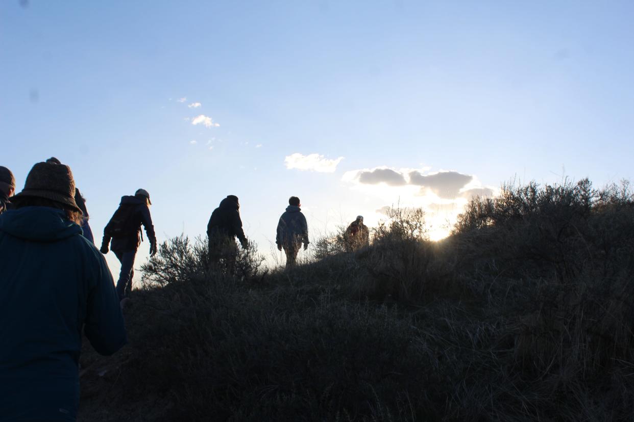 A line of hikers ascends the face of the cliffs at First Peoples Buffalo Jump State Park