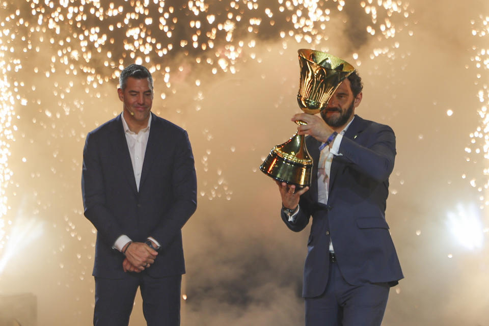 Spanish former basketball player Jorge Garbajosa, right, holds the championship trophy during the FIBA World Cup 2023 draw in Quezon city, Philippines on Saturday April 29, 2023. (AP Photo/Josefino de Guzman)