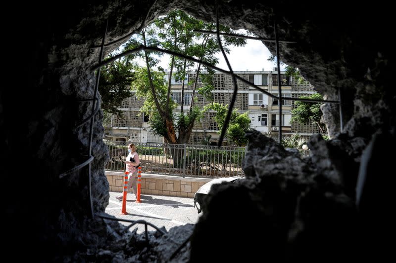 FILE PHOTO: A woman is seen through a wall of a residential building which was damaged by a rocket launched overnight from the Gaza Strip, in Ashkelon