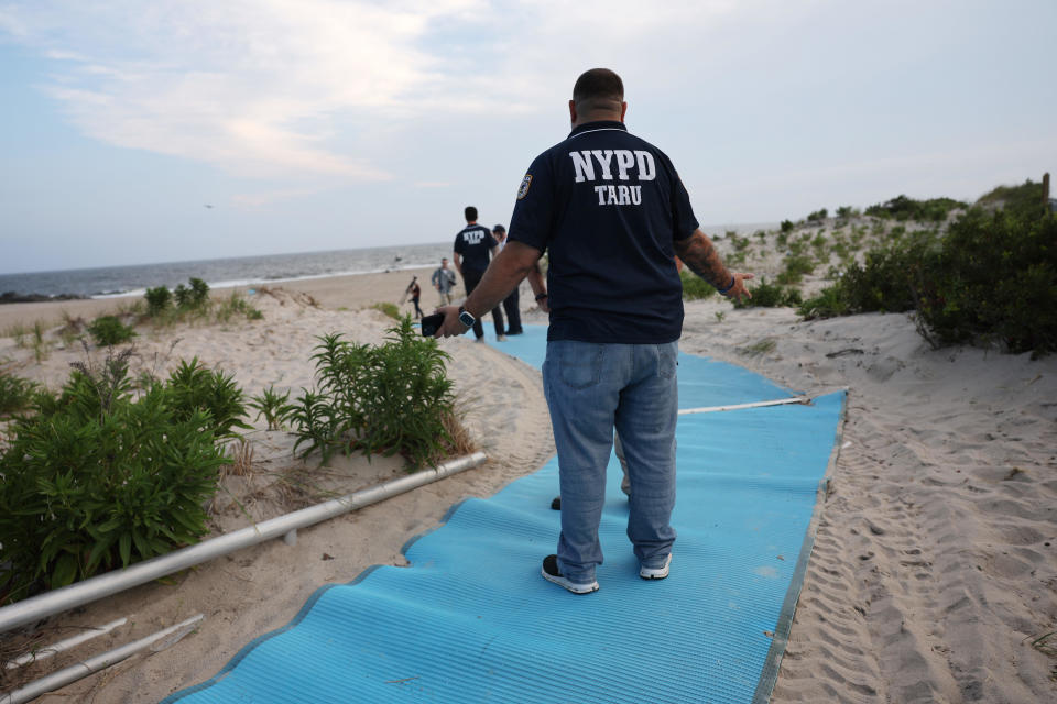 Police gather along Rockaway Beach after a woman was attacked by a shark in the early evening on August 7, 2023 in New York City.  / Credit: Getty Images